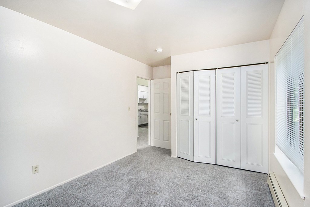 A room with white walls and a grey carpet.