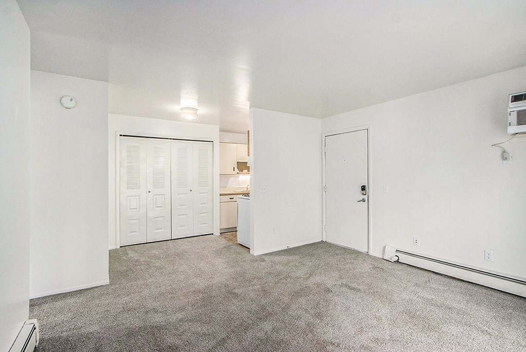 A large empty room with a carpeted floor and white walls
