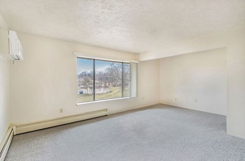 A living area with a large window overlooking trees at Concord Place Apartments, Kalamazoo, MI, 49009
