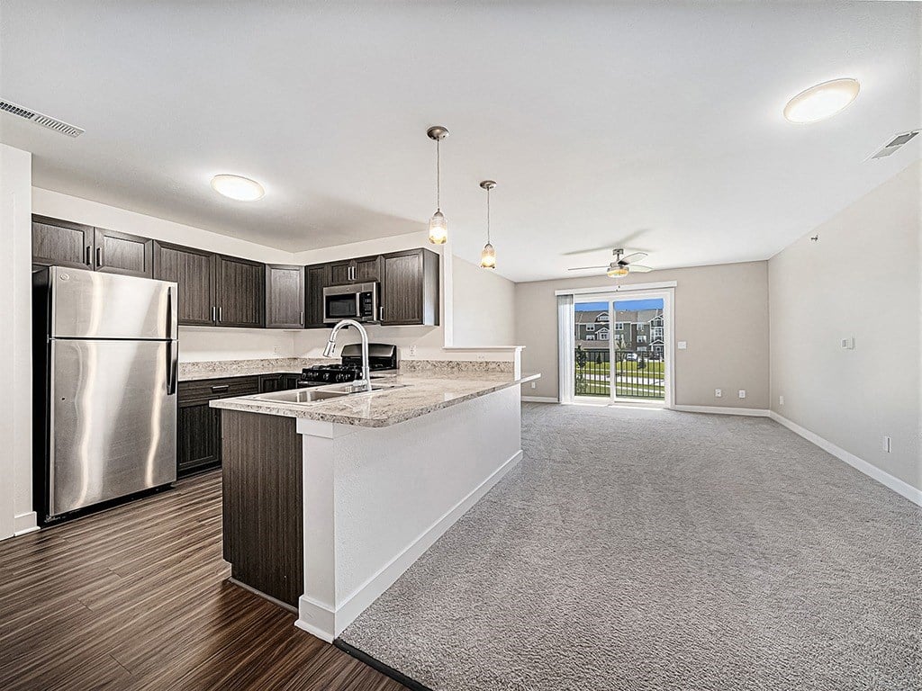 A kitchen with a refrigerator, microwave, and a countertop with a sink at Copper Creek Apartment Homes, Maize, Kansas