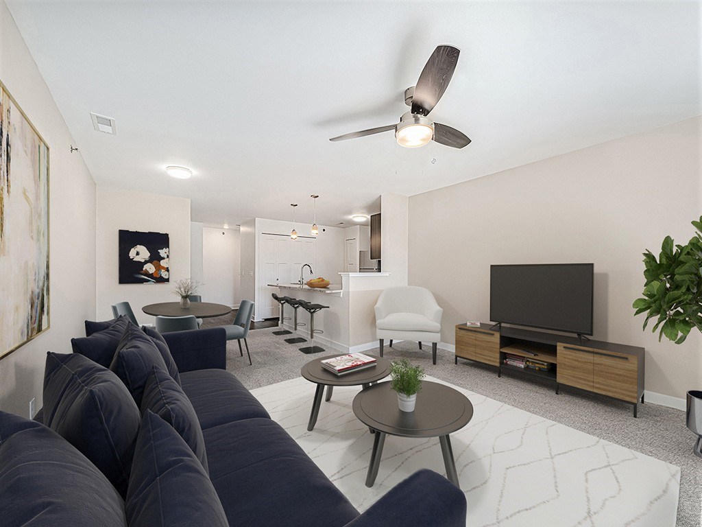 A living room with a dark blue sofa and a television at Copper Creek Apartment Homes, Maize, Kansas