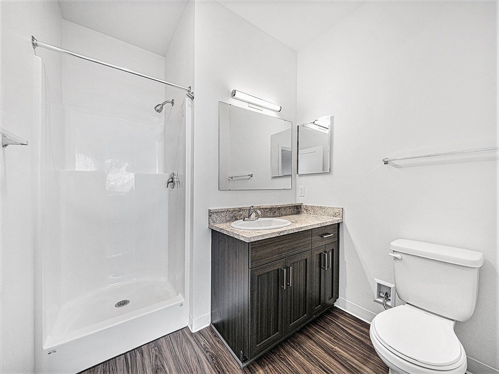 A white toilet sits next to a sink in a bathroom an empty bedroom with a ceiling fan and ensuite at Copper Creek Apartment Homes, Kansas, 67101