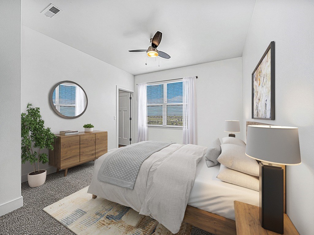 A bedroom with a bed, a ceiling fan, and a window with blinds at Copper Creek Apartment Homes, Maize, Kansas