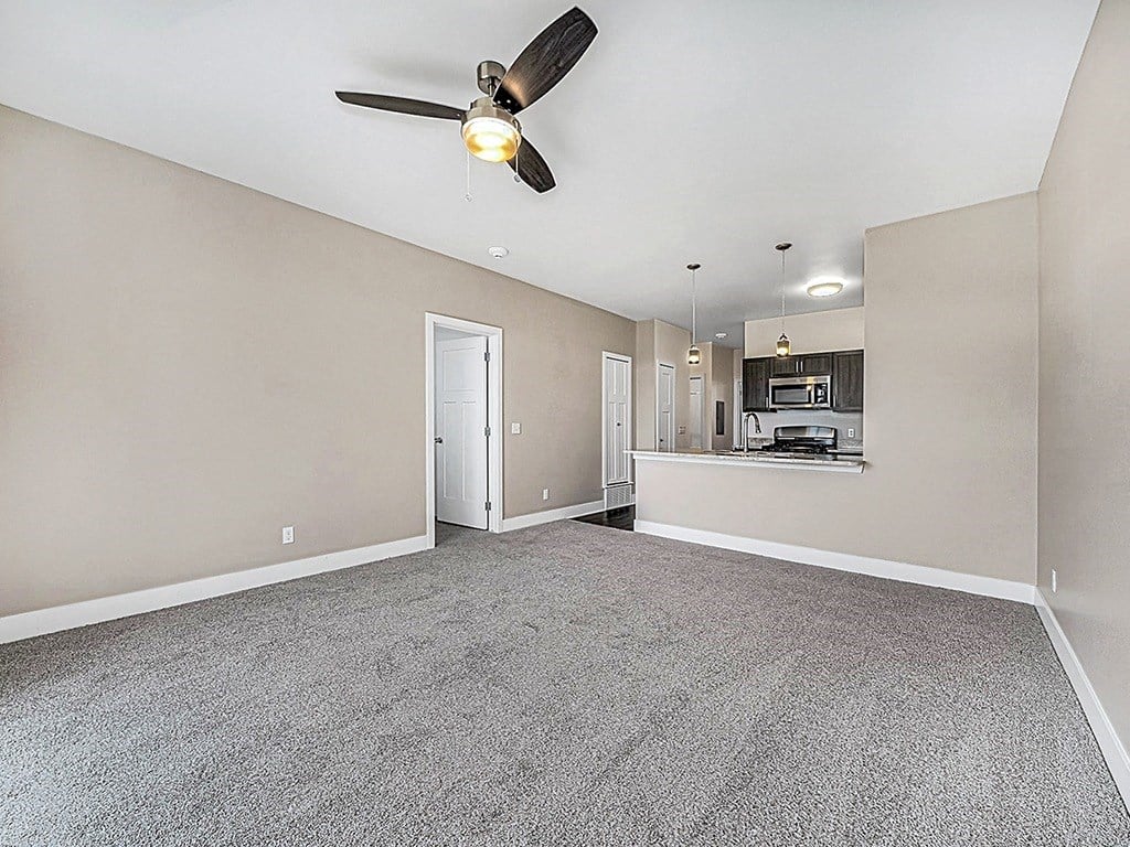 A living room with a ceiling fan and carpeted floor an empty bedroom with a ceiling fan and ensuite at Copper Creek Apartment Homes, Kansas, 67101