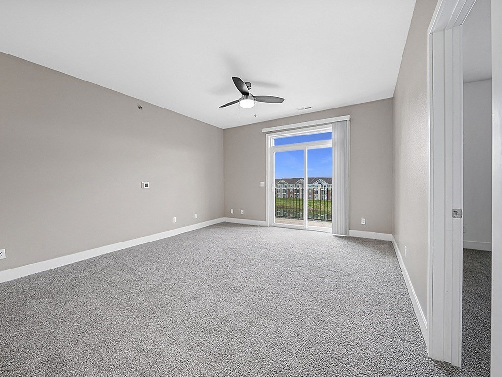 A living room with a 9' ceiling and a ceiling fan an empty bedroom with a ceiling fan and ensuite at Copper Creek Apartment Homes, Kansas, 67101
