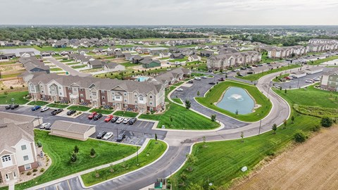 A bird's eye view of a residential area with houses, a roundabout, and a parking lot.