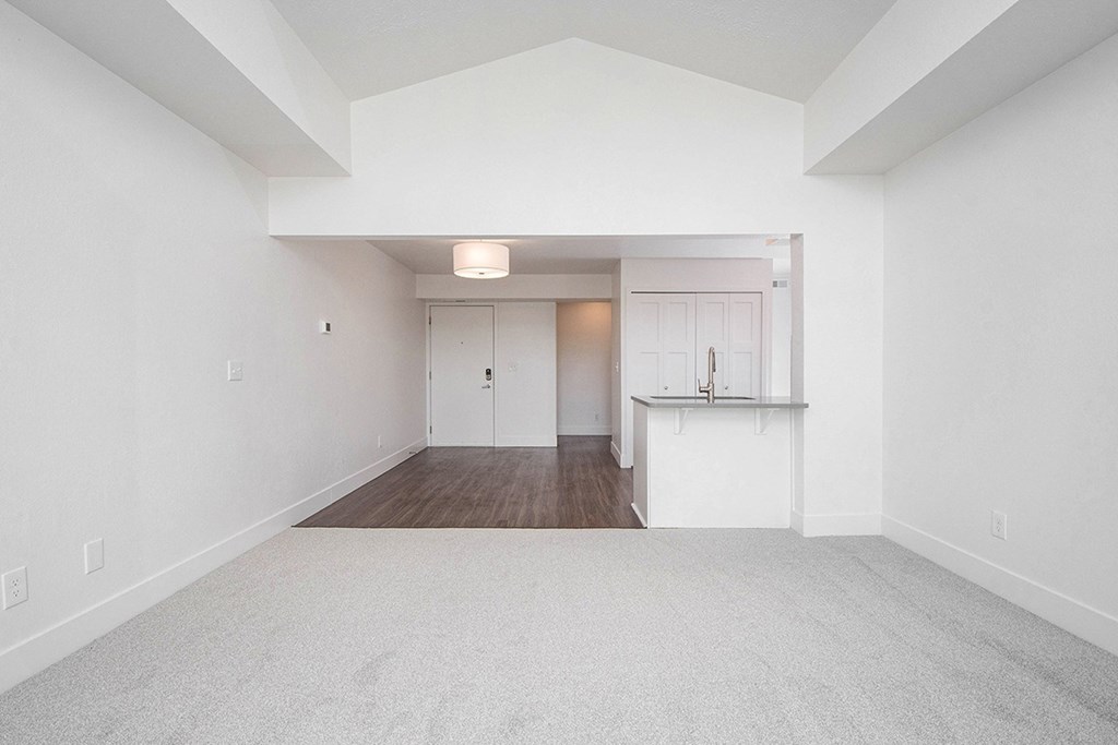 A large, empty living and dining room with a carpeted floor at The Crossings Apartments, Grand Rapids, MI, 49508