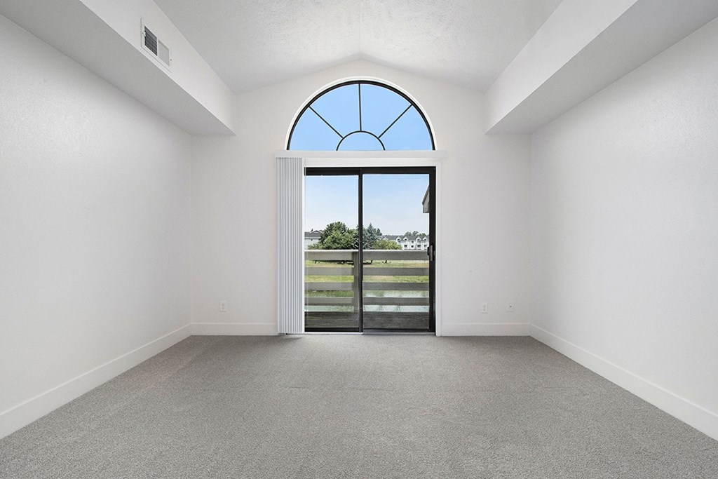 A living room with a cathedral ceiling and large arched window and a view at The Crossings Apartments, Grand Rapids, MI, 49508