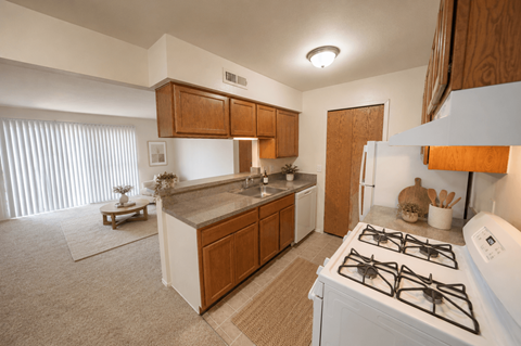 A kitchen with a white stove top oven and wooden cabinets.