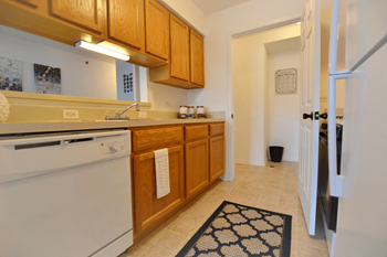 a kitchen with white appliances and wooden cabinets at Northport Apartments, Michigan