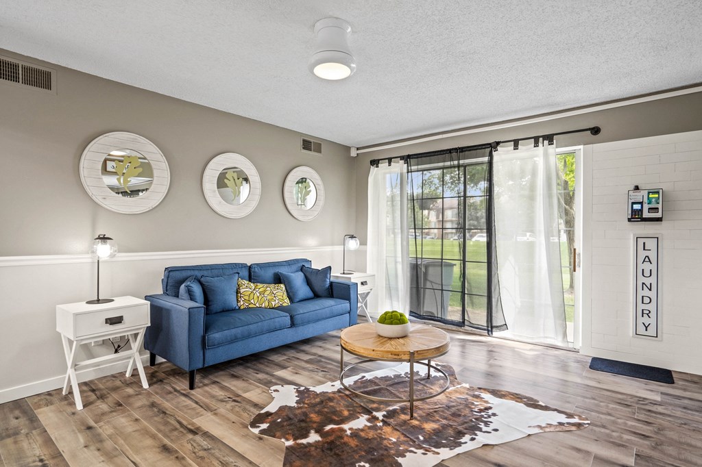a living room with a blue couch and a coffee table at Beacon Hill and Great Oaks Apartments, Rockford, IL