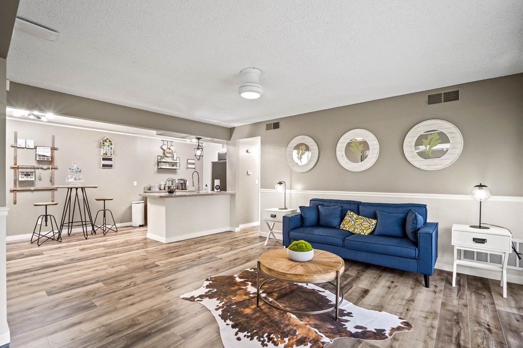 a living room with a blue couch and a coffee table in front of a kitchen with a at Beacon Hill and Great Oaks Apartments, Rockford, IL, 61109