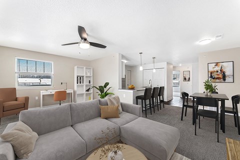 A living room with a grey couch and a ceiling fan.