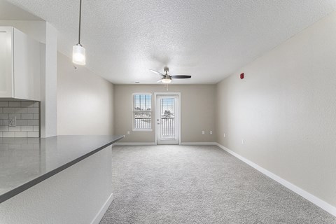 A spacious living room with a ceiling fan and a door leading to a patio at Eagle Ridge Apartment Homes, Traverse City, Michigan