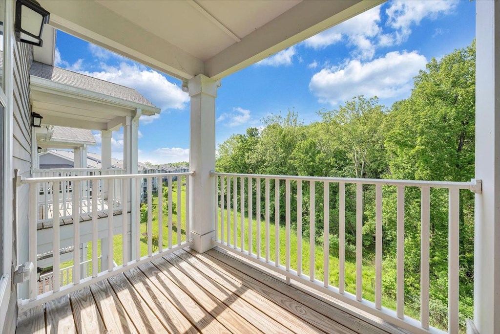 the view from the deck of a home with trees and a blue sky
