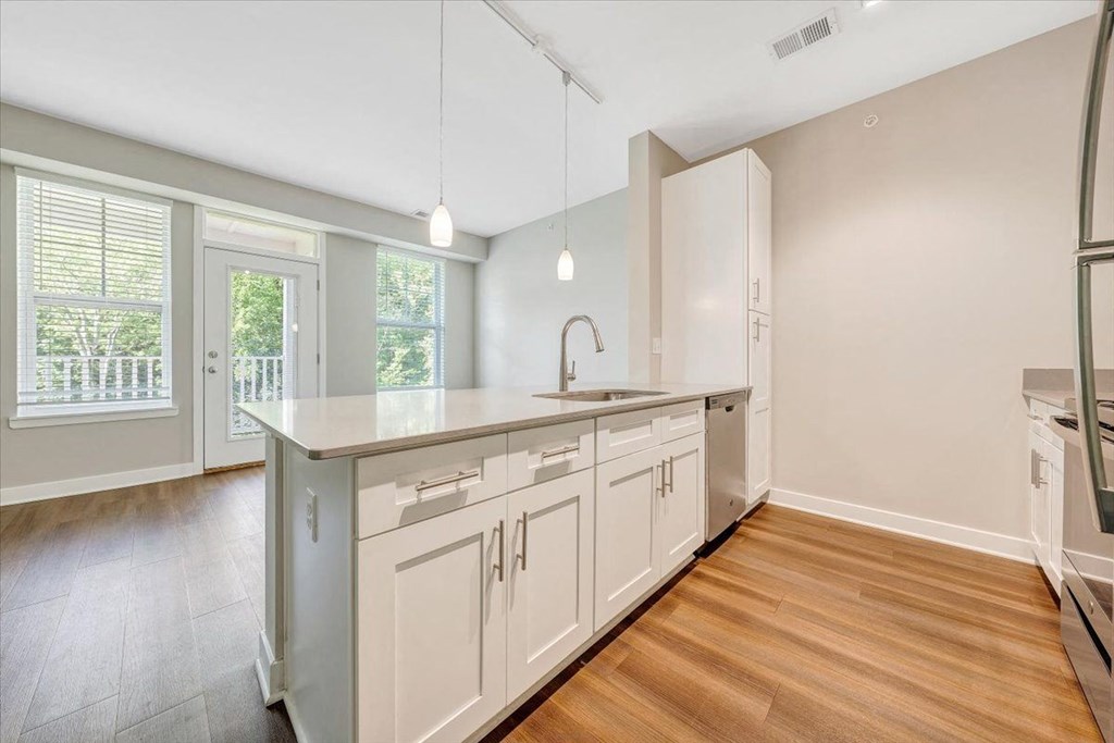 a large kitchen with white cabinets and a wooden floor