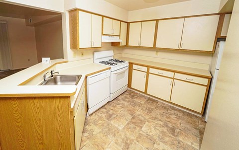 A kitchen with wooden cabinets and a white stove top oven.