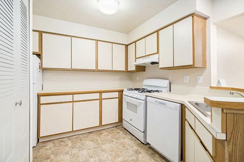 A kitchen with a white stove and white dishwasher at Emerald Park Apartments, Michigan