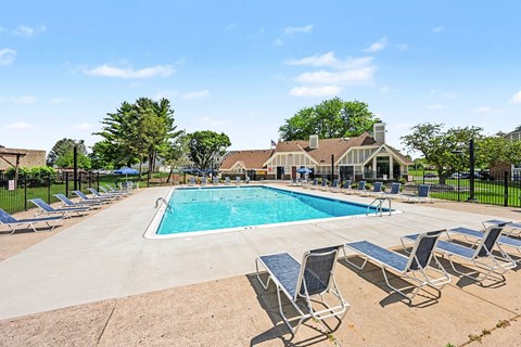 Outdoor swimming pool with lounge chairs and clubhouse at Fairlane Apartments, Springfield, MI