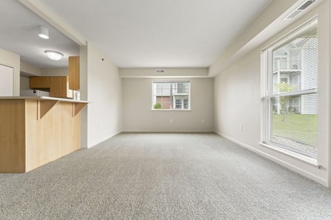 An enlarged living room with a carpeted floor and a window with blinds at Fieldstream Apartment Homes in IA 50023