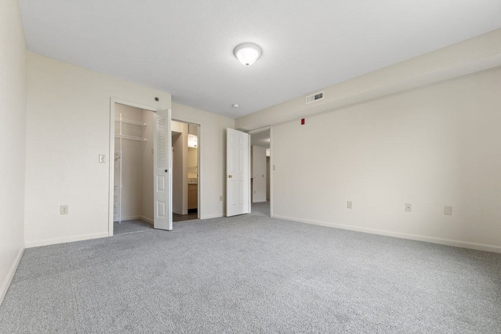 A large empty bedroom with an attached bathroom and a walk-in closet at Fieldstream Apartment Homes in IA 50023