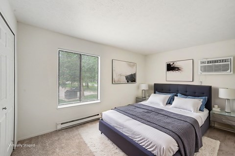 A bedroom with a bed, nightstands, and pictures on the wall.