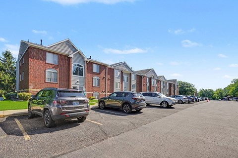 A parking lot with cars and apartment buildings in the background.
