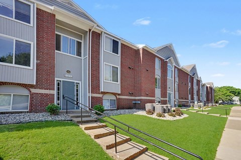 A row of red brick apartment buildings with green lawns in front.