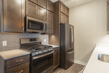 a kitchen with dark wood cabinets and stainless steel appliances at 24 at Bloomfield, Bloomfield Township, MI, 48302