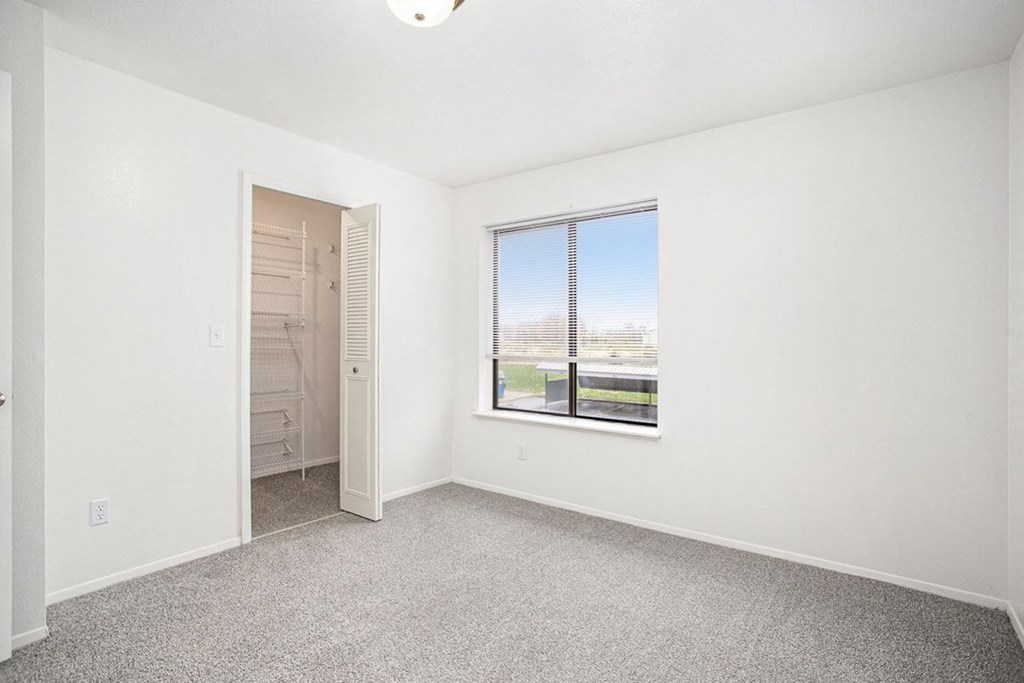 a bedroom with a large window and a walk in closet at Glenn Valley Apartments in Battle Creek, MI