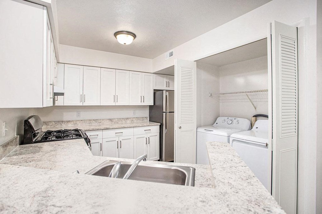 a kitchen with white cabinets and a washer and dryer at Glenn Valley Apartments in Battle Creek, MI