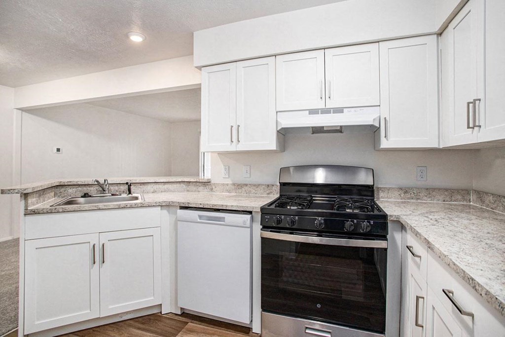 an upgraded kitchen with white cabinets and a stove and a dishwasher at Glenn Valley Apartments in Battle Creek, MI