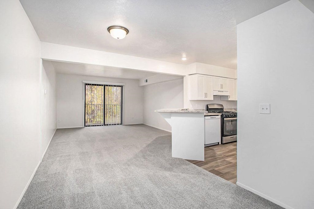 a living room and kitchen with a door to a balcony at Glenn Valley Apartments in Battle Creek, MI