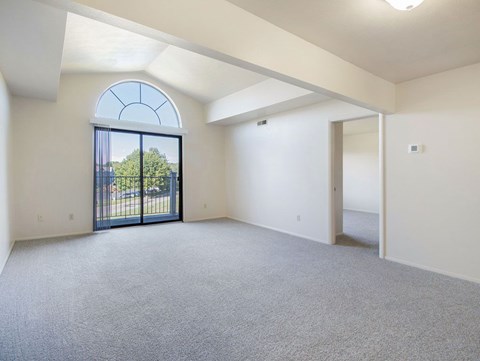 A spacious living room with a cathedral ceiling, large arched window and a balcony with a view at Glenn Valley Apartments, Michigan, 49015