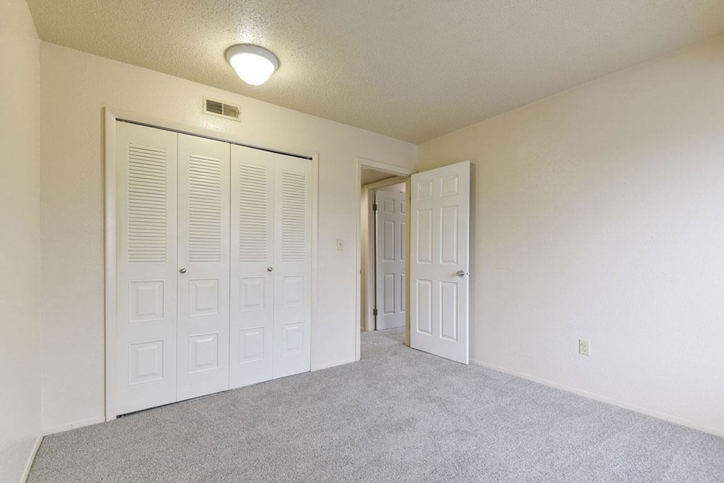 A bedroom with large closet and grey carpet at Granada Apartments, Jackson, 49202