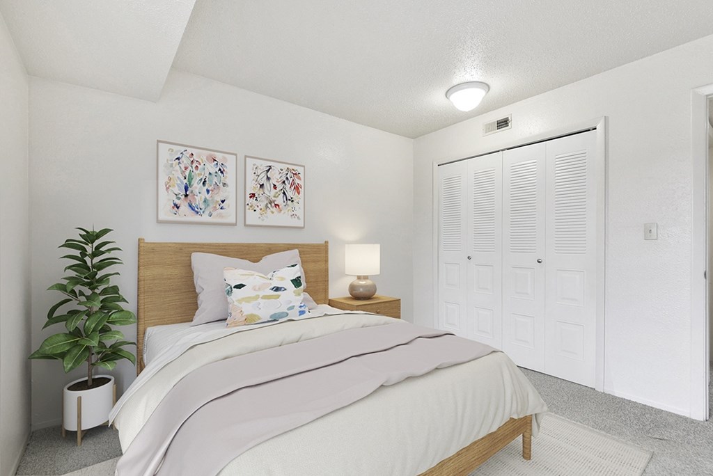 A bedroom with a large closet, bed, and a potted plant at Granada Apartments, Jackson, 49202