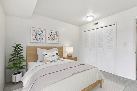 Bedroom with wood bed frame and white closet doors at Granada Apartments, Jackson, MI 49202