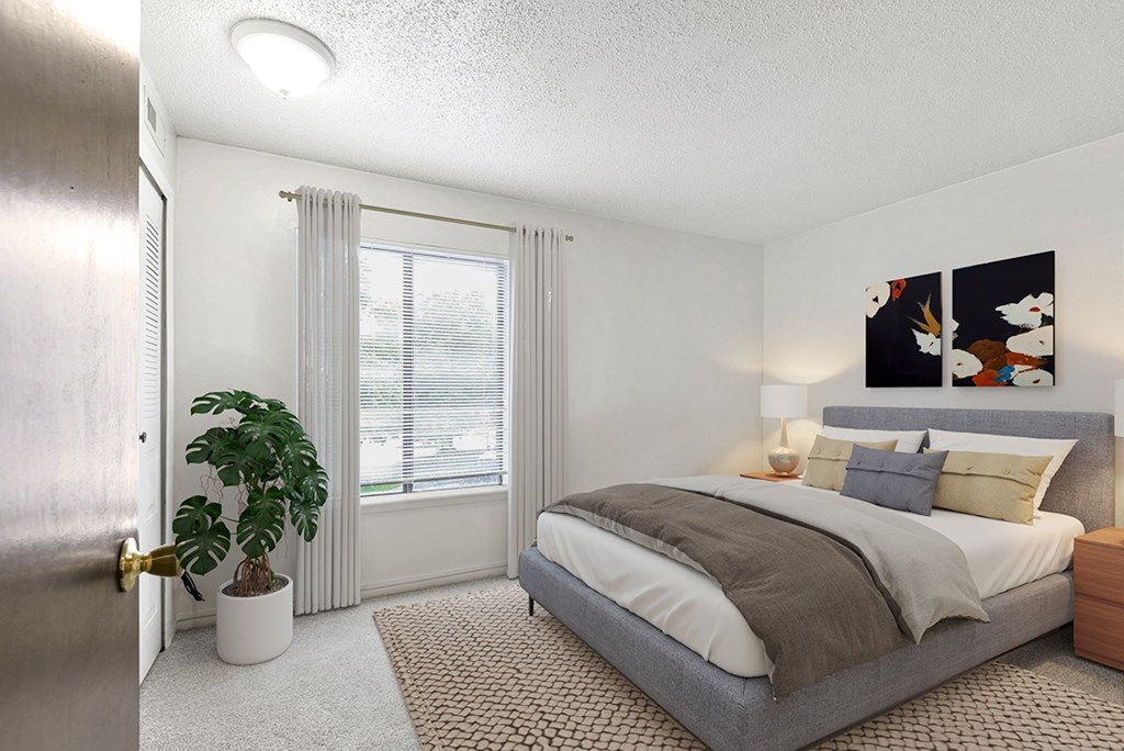A bedroom with a bed, large window, and a plant at Granada Apartments, Jackson, 49202