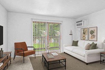 A living room with a white couch leading to a balcony at Granada Apartments, Jackson, 49202