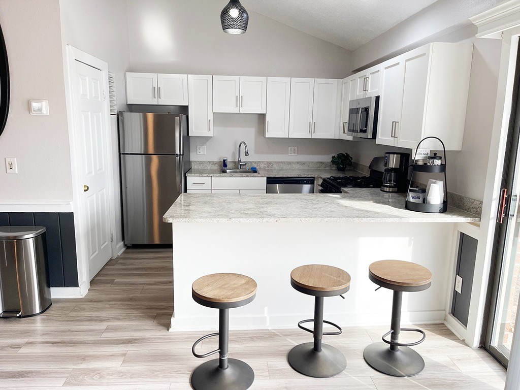 A community building kitchen with white cabinets and a breakfast bar at Granada Apartments, Jackson