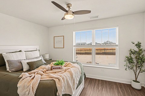 A bedroom with a bed, large windows and a ceiling fan at The Grove Apartment Homes, Nebraska