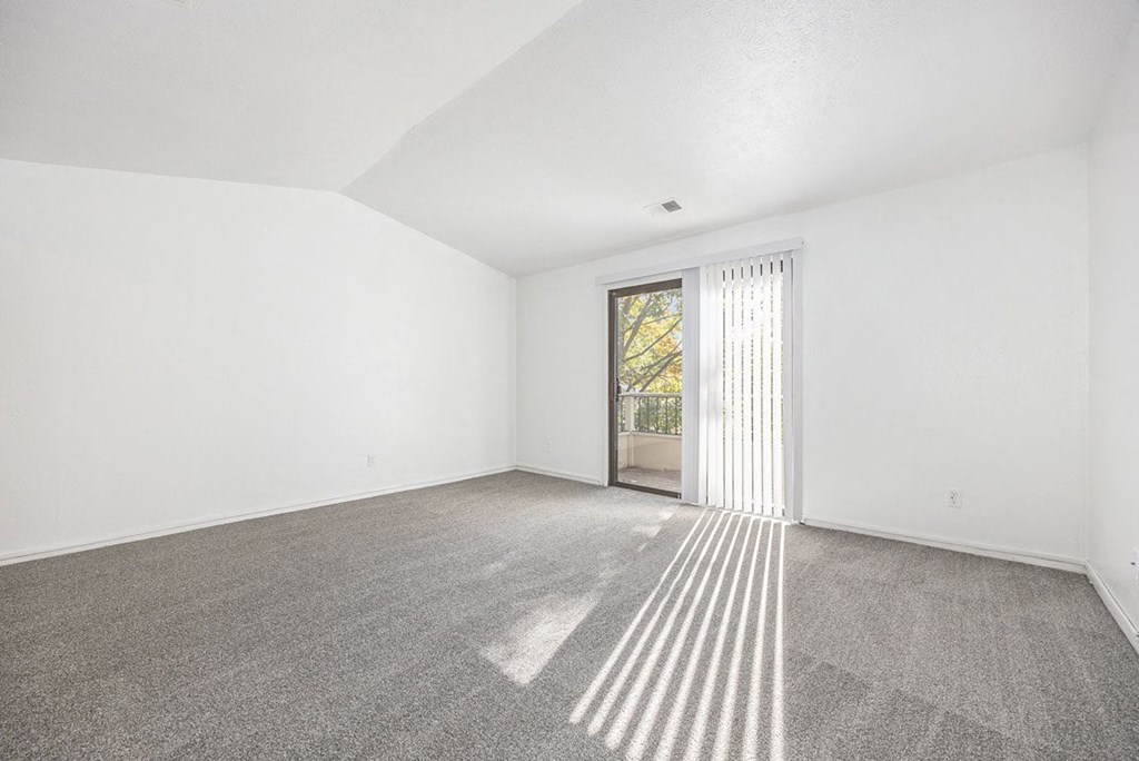 an empty living room with a cathedral ceiling and carpeting at Hampton Lakes Apartments, Michigan, 49534