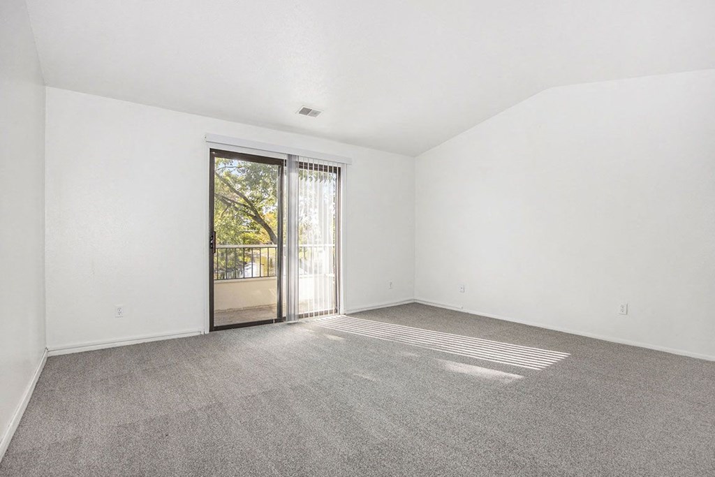 living room with a cathedral ceiling and sliding glass door to a balcony at Hampton Lakes Apartments, Michigan, 49534