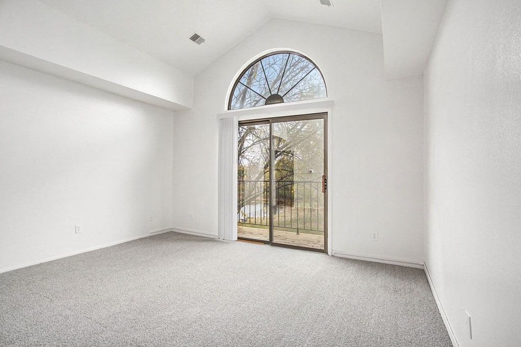 a living room with a cathedral ceiling and door to a balcony at Hampton Lakes Apartments, Michigan, 49534