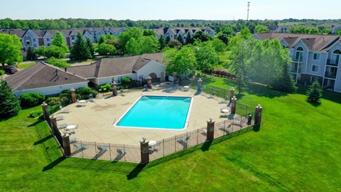 Outdoor pool area with fenced sundeck and clubhouse at Heatherwood Apartments, Grand Blanc, Michigan