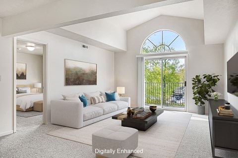 A living room with a large window and a painting on the wall.