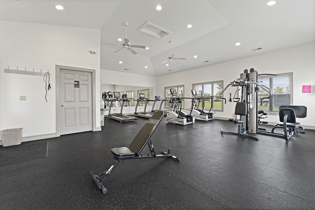 A spacious gym with a variety of equipment including a treadmill, a stationary bike, a rowing machine, and a weight bench at Hunters Pond Apartment Homes, Illinois, 61820