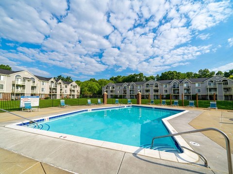 Outdoor swimming pool with lounge chairs and fencing at Hurwich Farms Apartments, South Bend, Indiana
