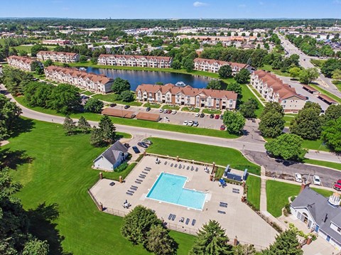 A large apartment complex with a swimming pool and a lake.