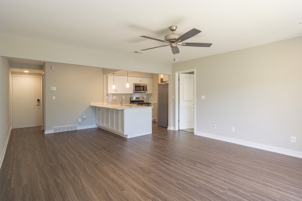 an empty living room with a kitchen in the background at Hillside Apartments, Michigan, 48393